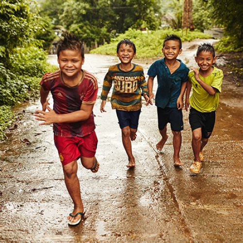 Rennende thaise kinderen in de regen.
