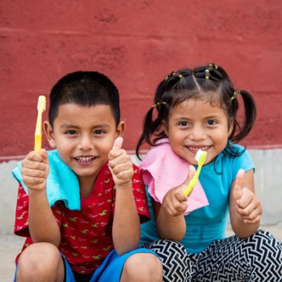 Twee sponsorkinderen met tandenborstel steken hun duim op.