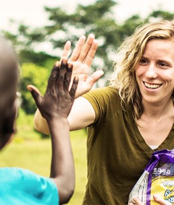 Een vrouw geeft een kind een high five.
