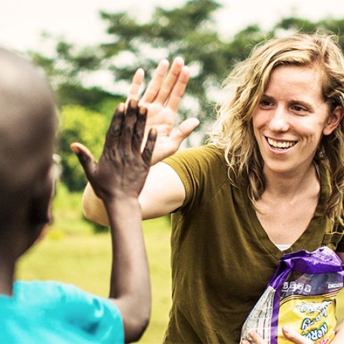 Een vrouw geeft een kind een high five.
