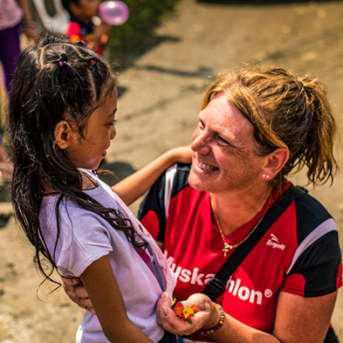 Vrouw in sportkleding lacht naar meisje.