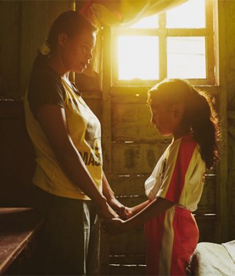 Een vrouw en haar dochter bidden samen.