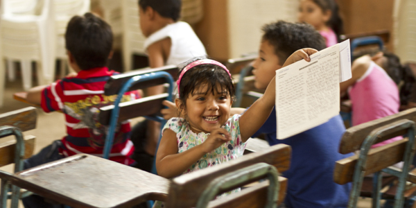 Meisje zit achterstevoren in de klas en houdt blij een brief omhoog