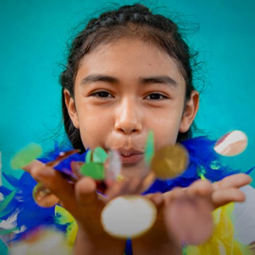 Meisje met sjaal van veren blaast confetti