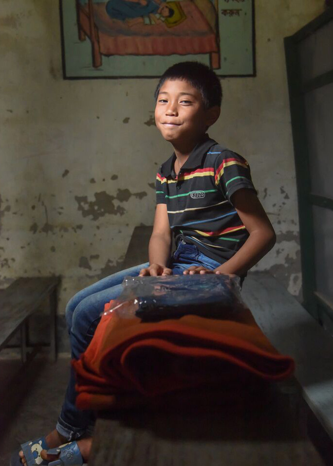 Whochong uit Bangladesh zit naast de dekens die hij met kerst kreeg