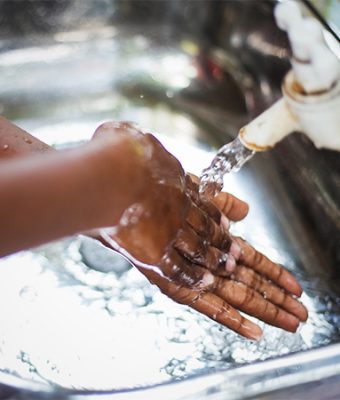 Een kind wast zijn handen bij een kraan.